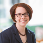 Smiling white woman with short red hair and glasses